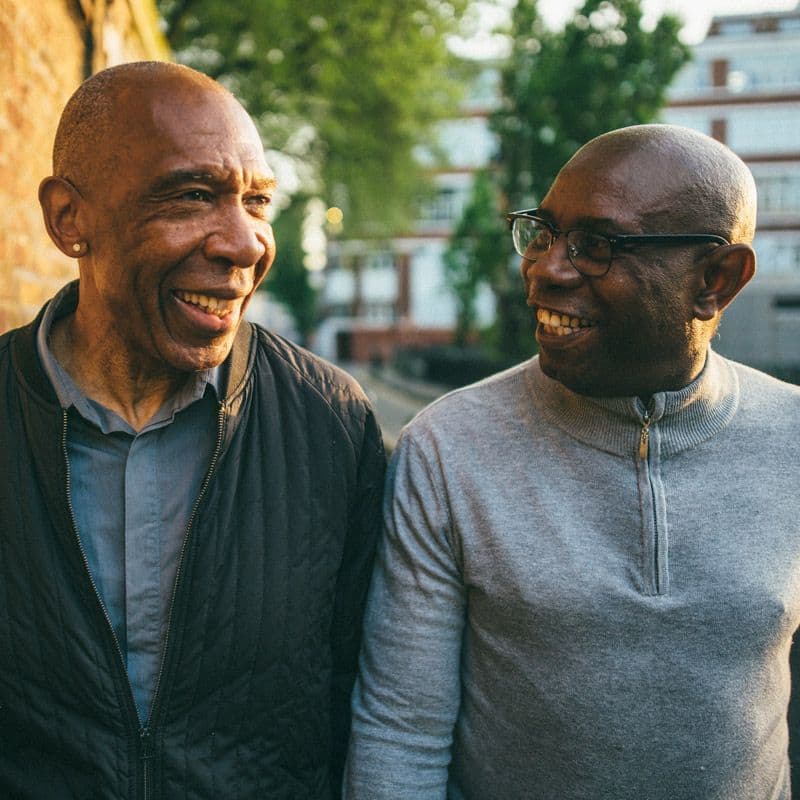 Two Black men chatting and walking down the street
