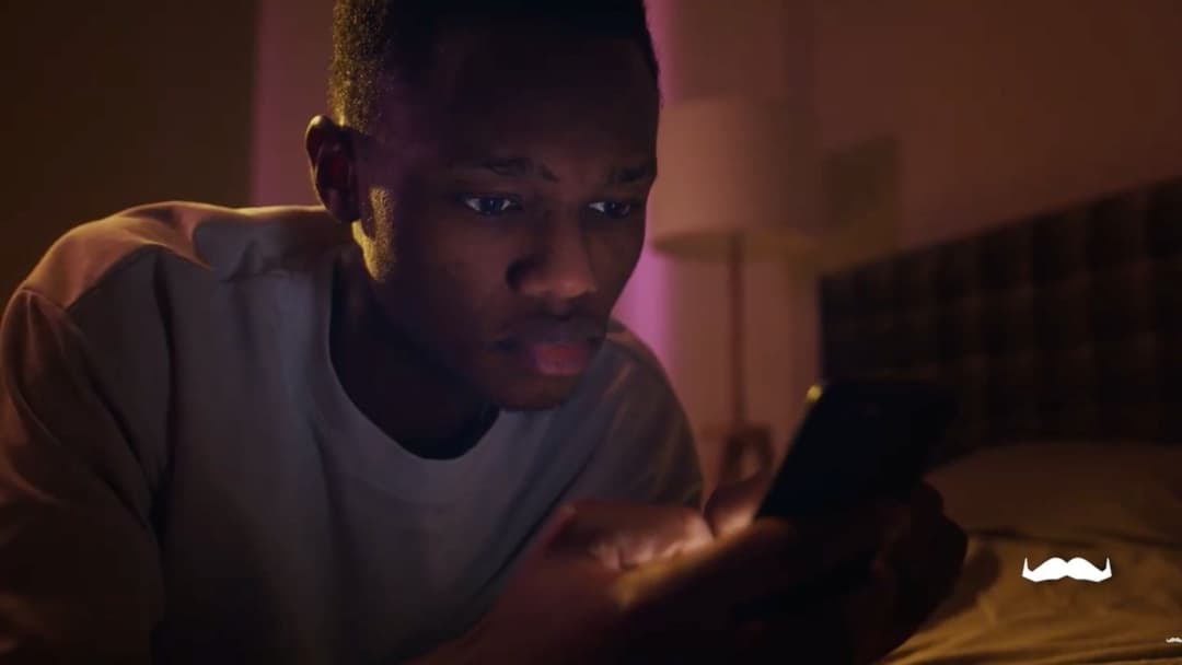 Photo of a young man looking engrossed into his smartphone.