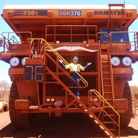 Frontal view of an orange mining truck featuring a white Movember logo.