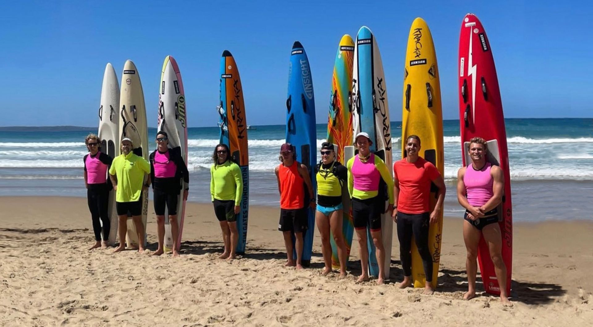Paddle boarders gather on the beach for a photo.