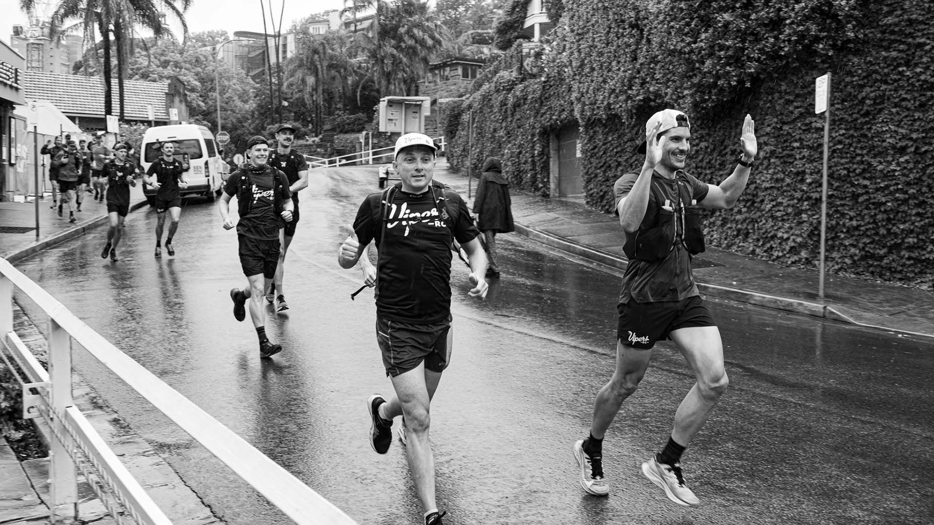 Black and white photo of running group running down a tree-lined street.
