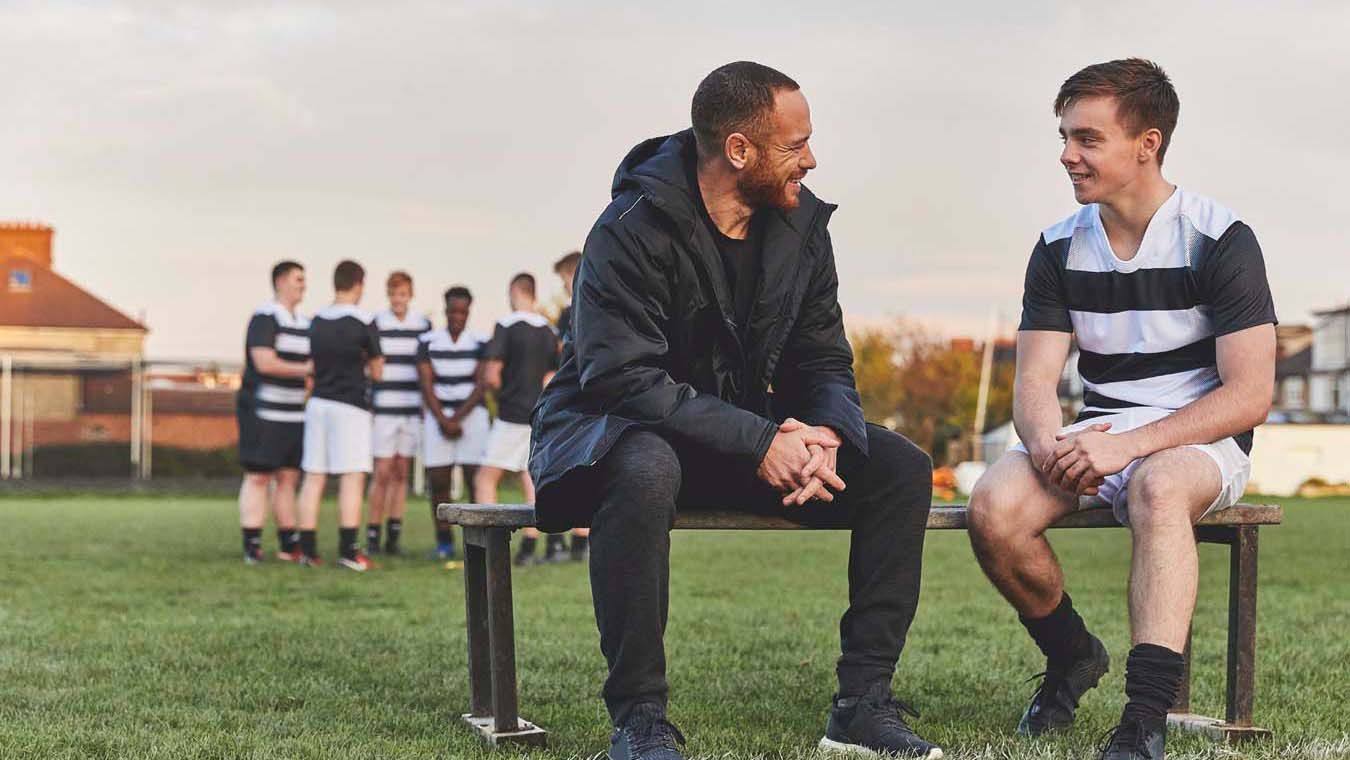 A photo of a coach talking to a young player. 