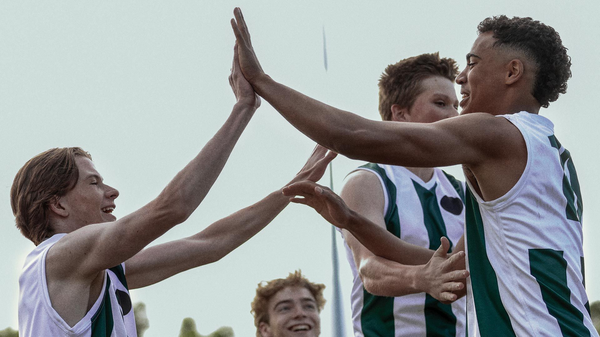 Young AFL players high-fiving.