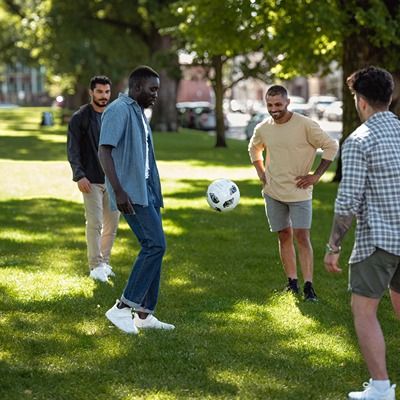 Young men kicking a football in a park.