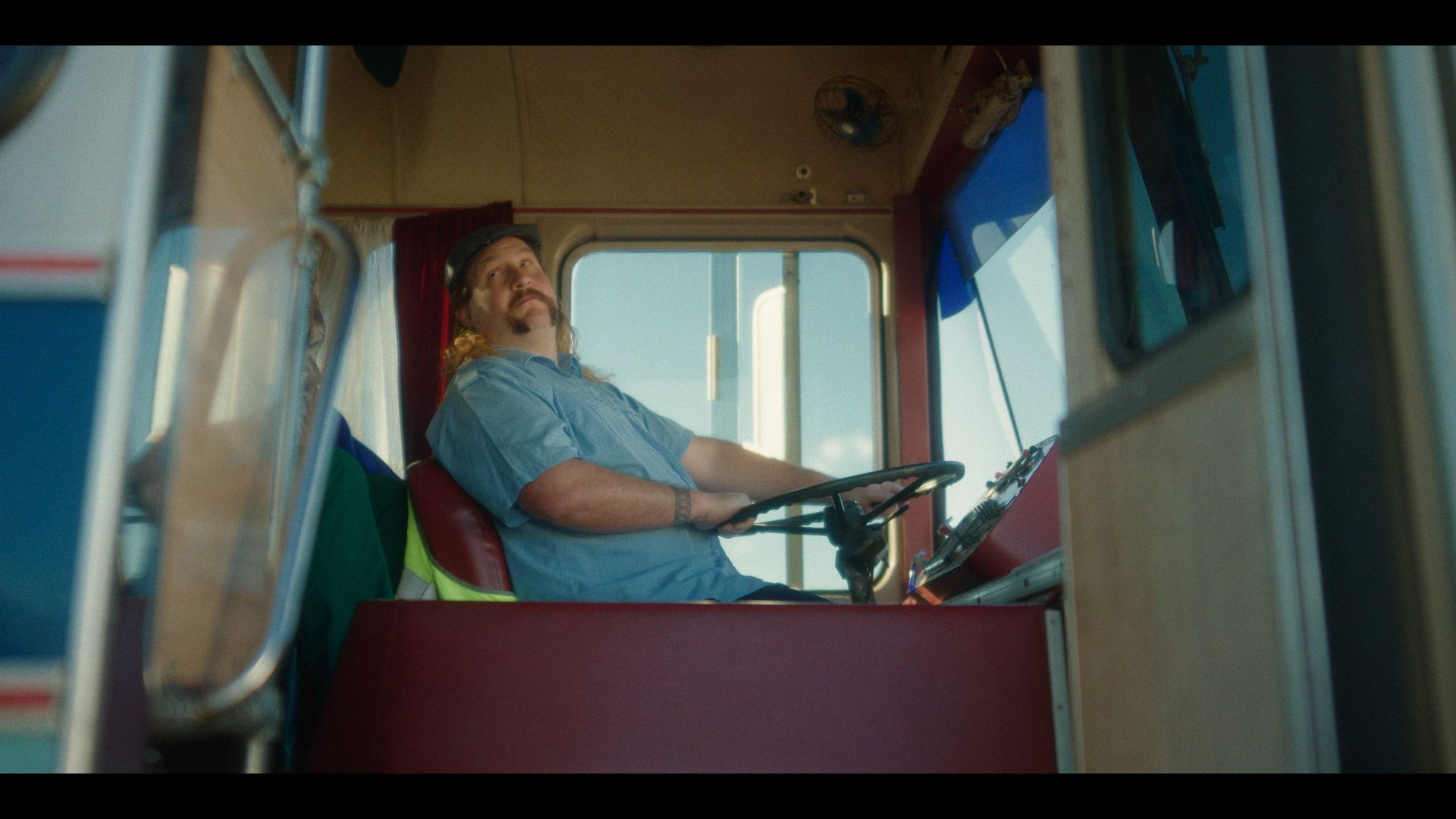 Bus driver sits in bus with door open looking out door for passengers to come aboard