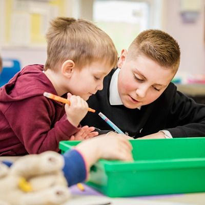 Photo of two young schoolboys drawing together.