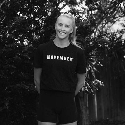 A photo of a Movember supporter Jenna Fulton, standing in Movember-branded activewear, smiling to camera.