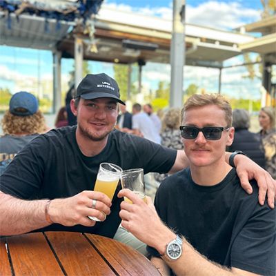 A photo of two young men enjoying a beer together.