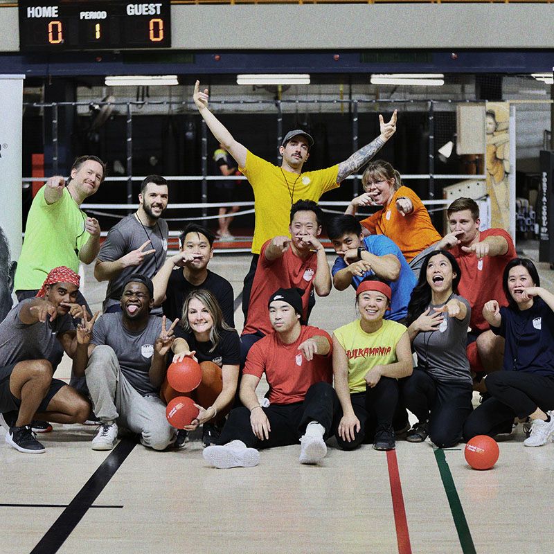 Photo of a dodgeball team, wearing bright active wear, posing enthusiastically to camera.