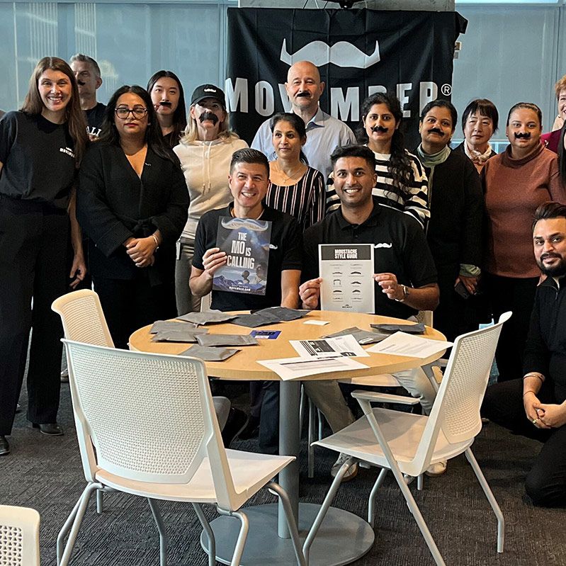 Photo of a group of people posing for a group shot at a Movember presentation.