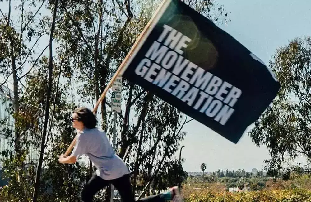 Person on skateboard, flying Movember flag.
