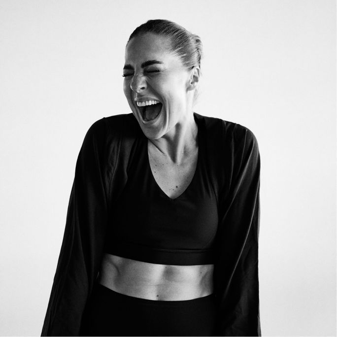 Black and white photo of athletic woman, laughing to camera.