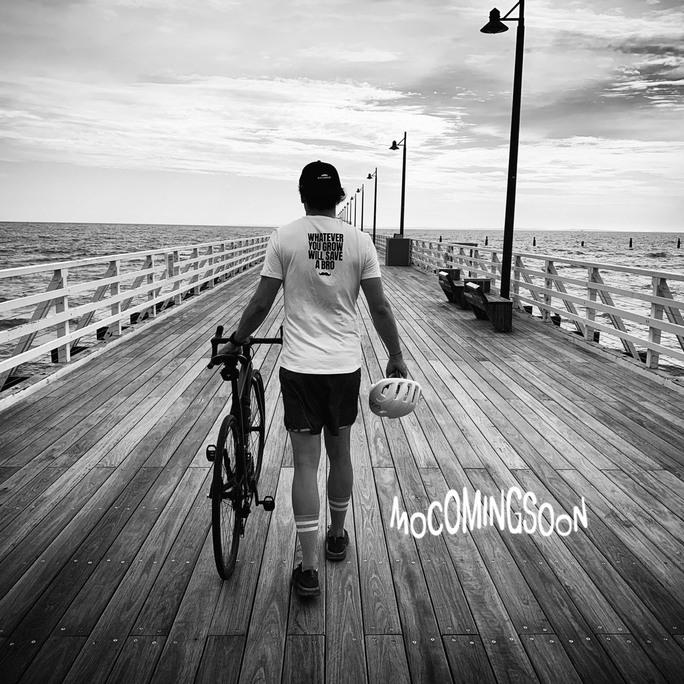 Cyclist walking his bicycle on beach pier.
