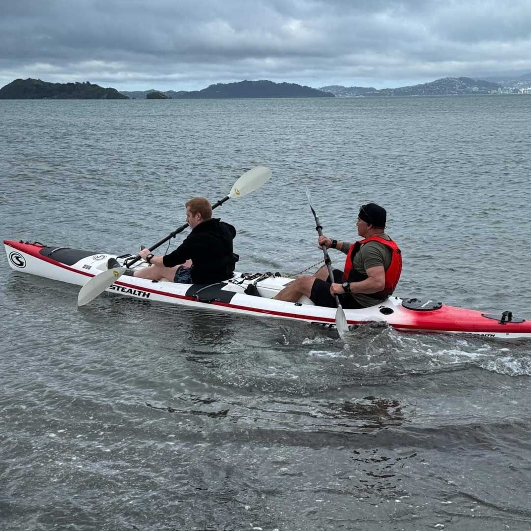 Photo of two men in a kayak on coastal water.