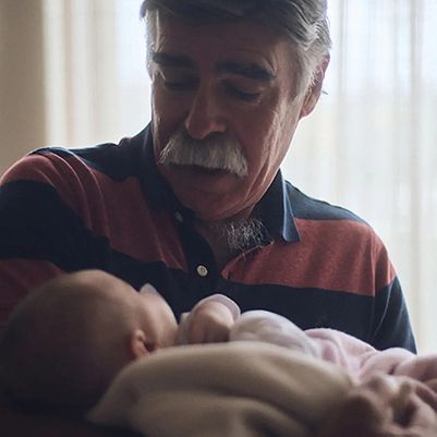 Photo of a grandfather lovingly cradling an infant.