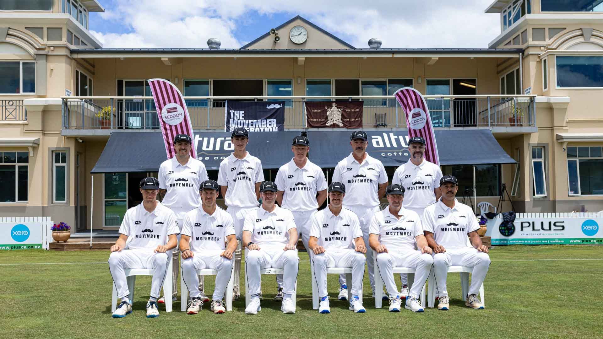 Photo of a cricket team in their cricket whites, posing on a cricket green in front of a club building.